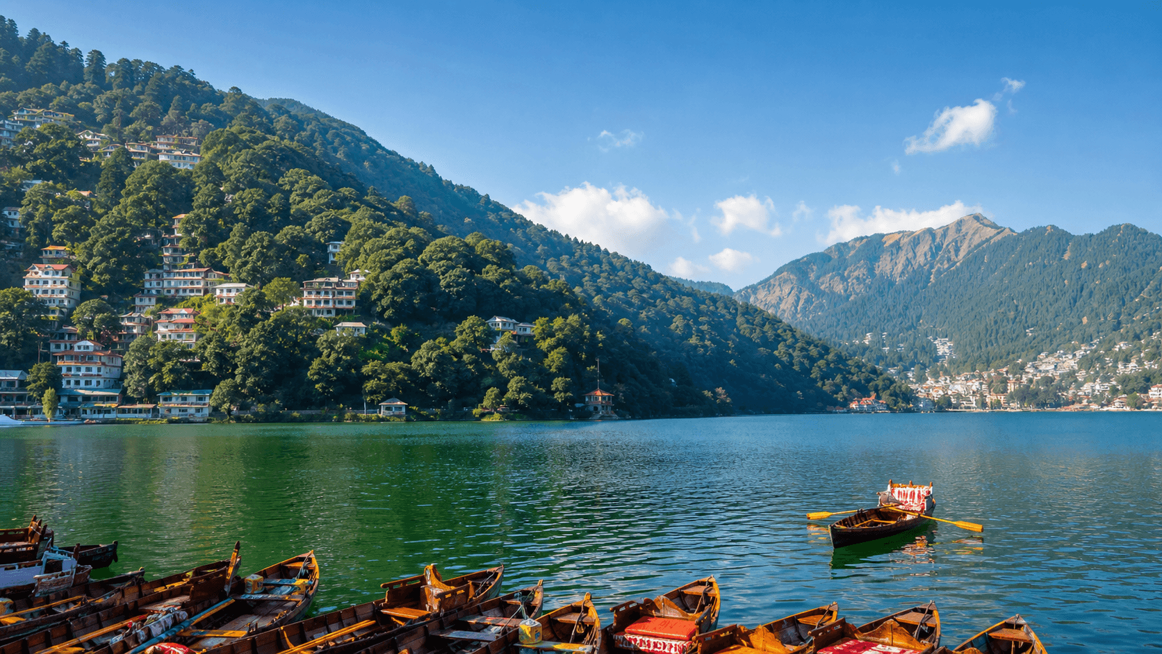 Naini Lake with boats, green hills, and lakeside buildings in Nainital